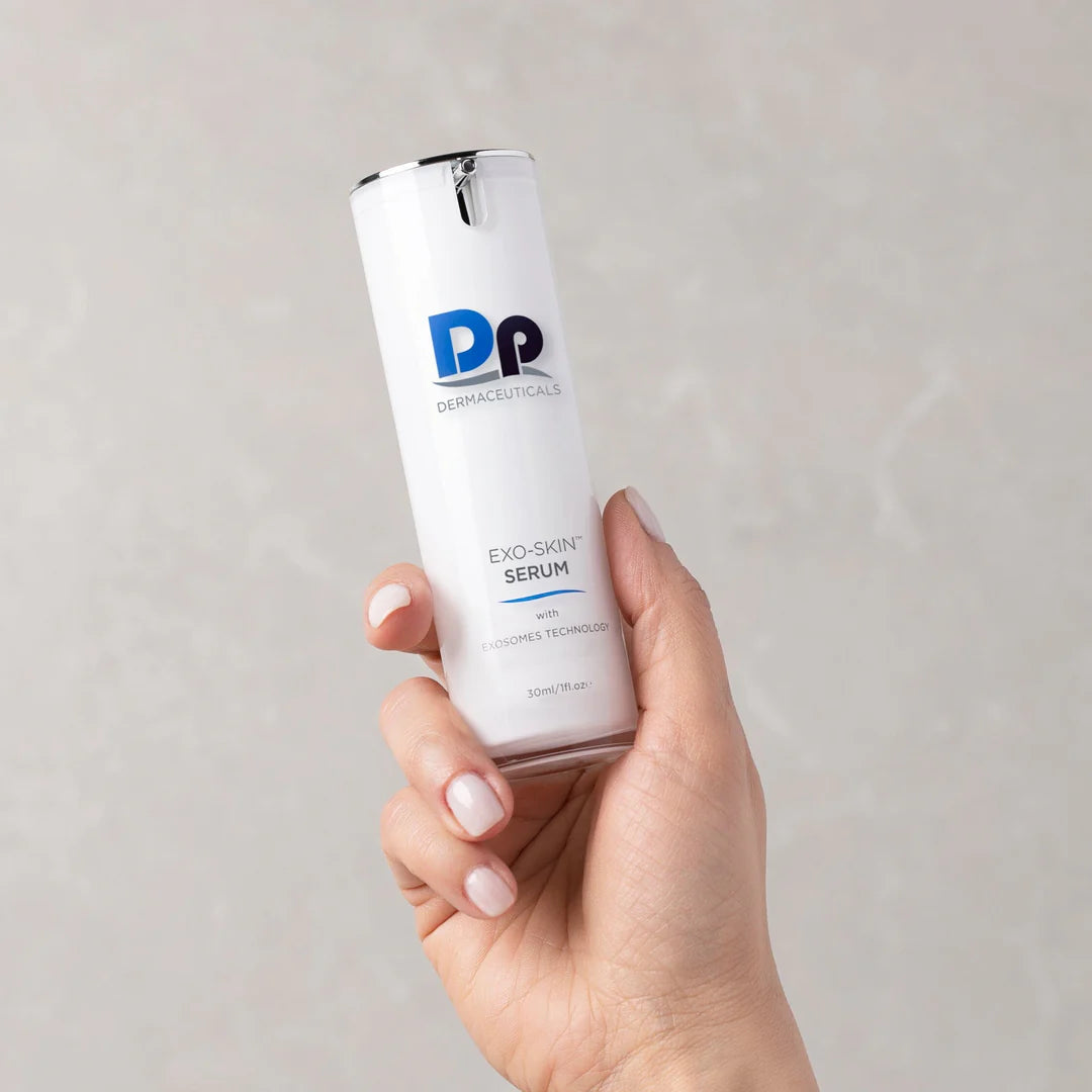 Hand holding a skincare serum bottle labeled 'DP Dermaceuticals' against a plain background